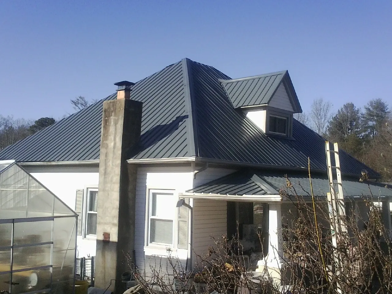 Dark blue standing seam metal roof on a white farmhouse with dormer — Slate & Tile Roof Repair by Roofing Brothers in Inchelium