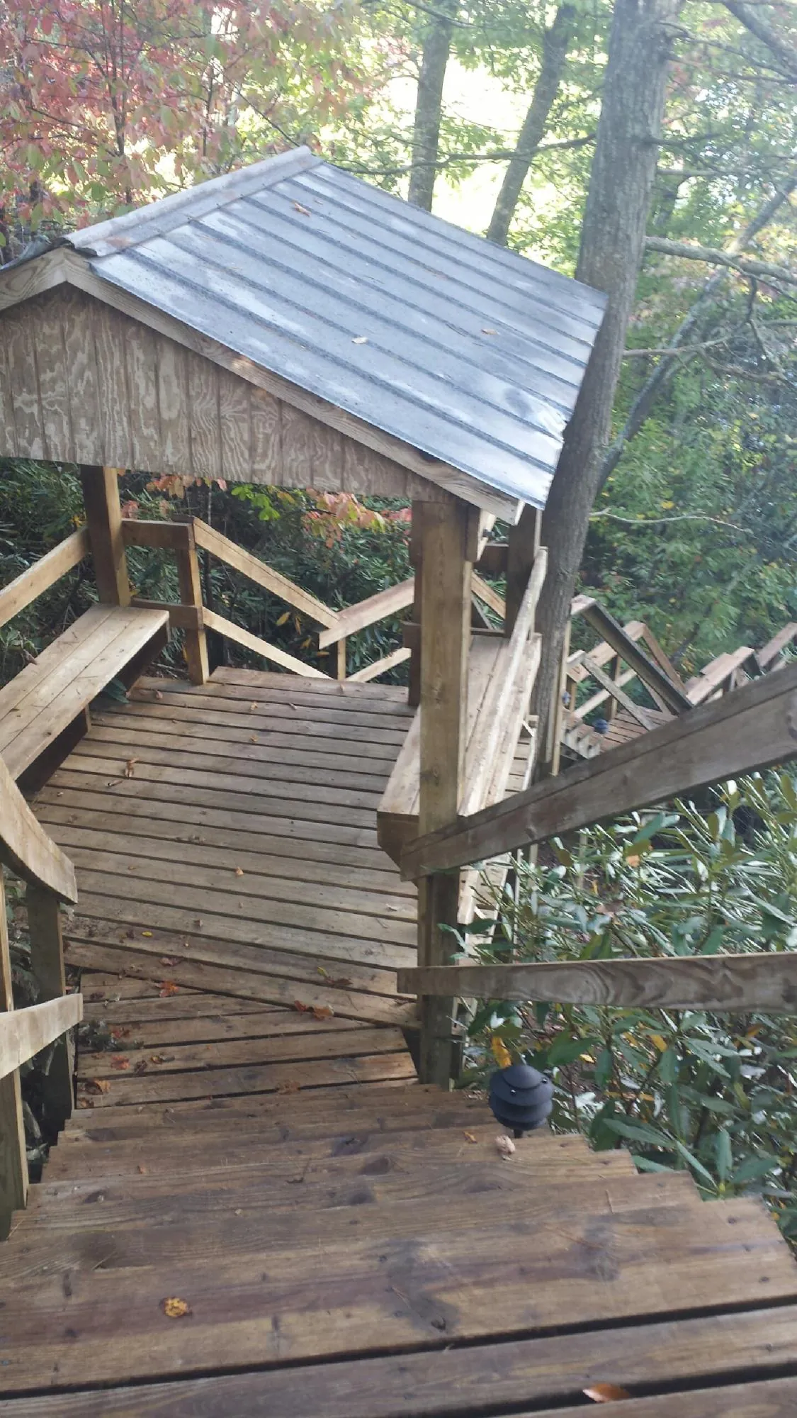 Metal roofed shelter over wooden steps on a wooded walkway — Skylight Repair & Installation work by our crew in Inchelium