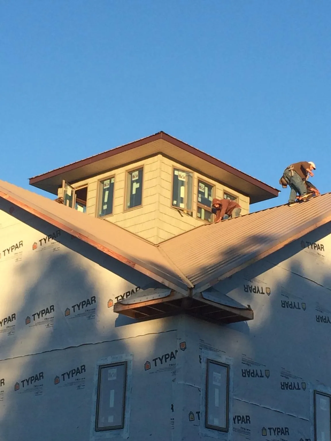 Roofers working around a rooftop cupola on a new metal roof at sunset — Roof Waterproofing in Inchelium by Roofing Brothers